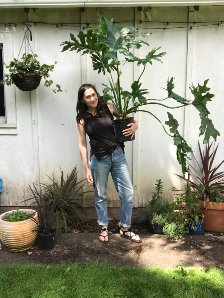 A woman holding a giant plant.